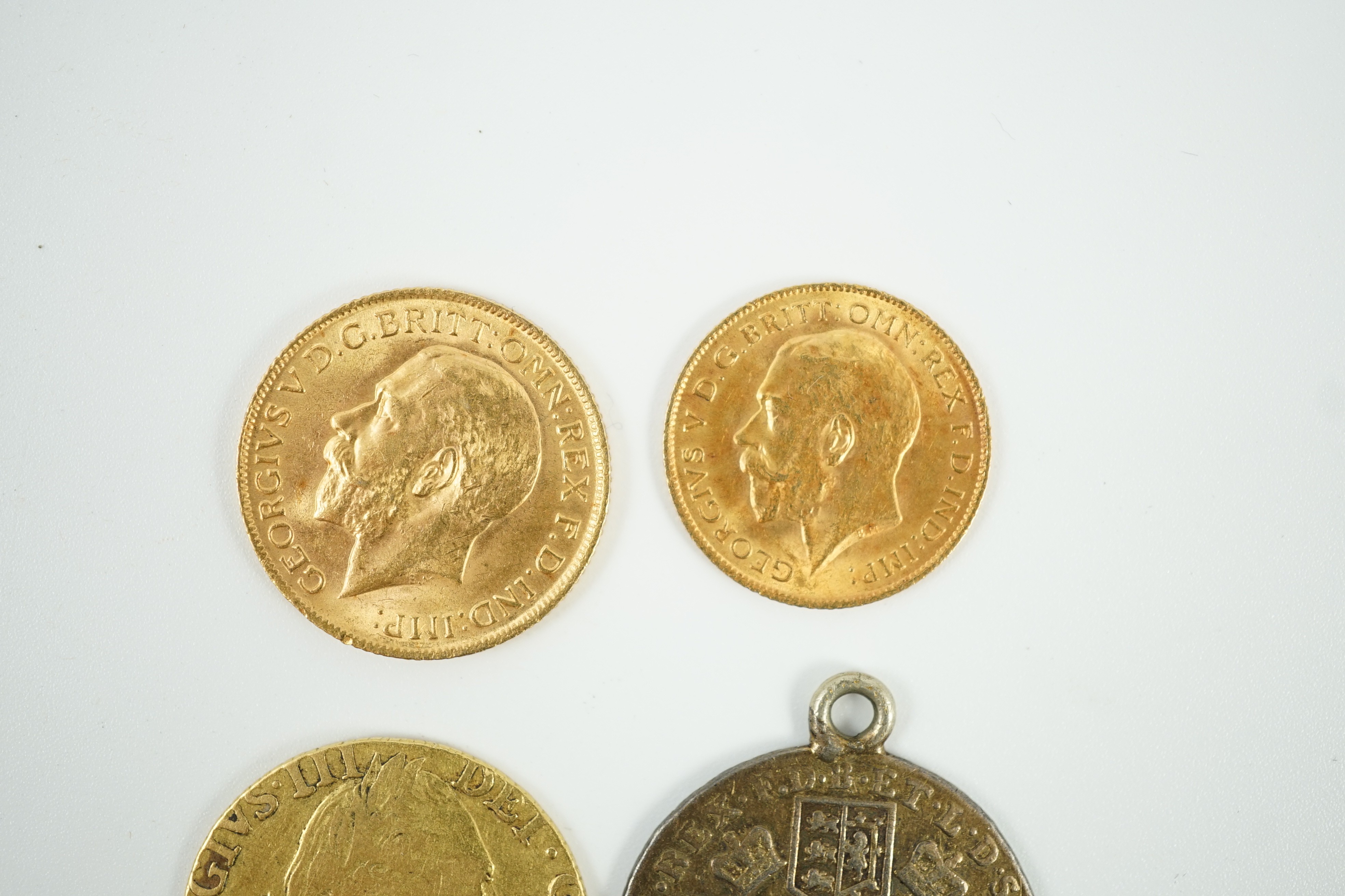 A George V 1915 gold sovereign and a 1915 gold half sovereign, a George III 1782 gold guinea(worn) and a George III 1787 shilling, with pendant mount.